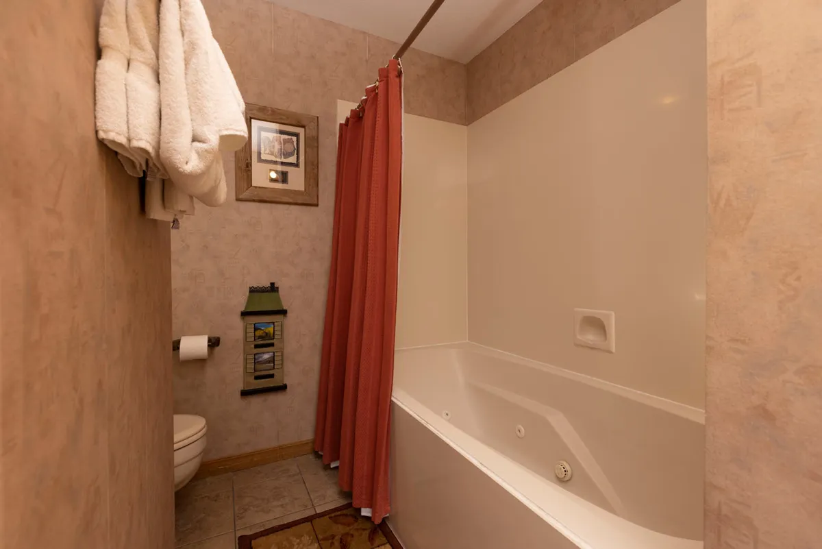 This image focuses on a soothing bathroom scene, featuring a bathtub with a shower curtain, a neatly arranged towel rack, a framed picture for visual interest, and soft lighting that creates a calming atmosphere. The setup invites thoughts of soaking or enjoying a peaceful morning routine, echoing the tranquil, restorative tone of the section.