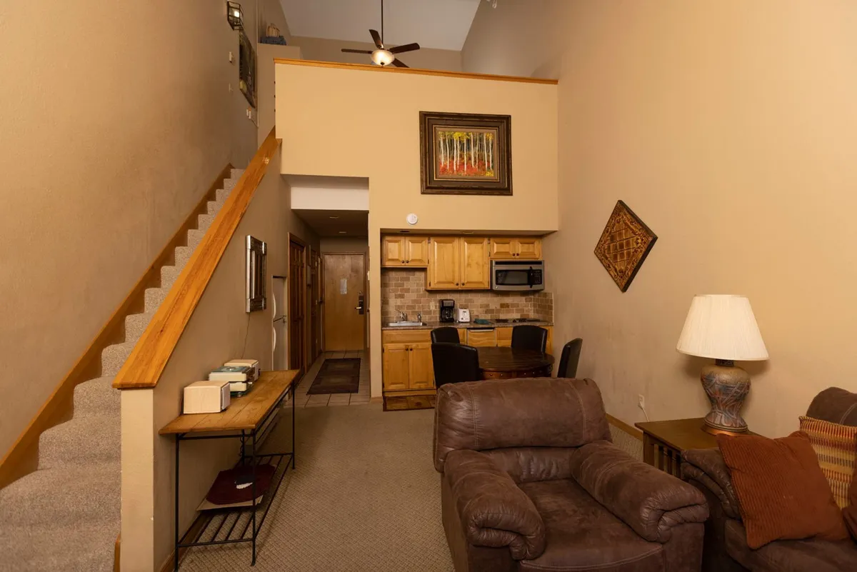A bright, open-concept kitchen and seating area with a modern staircase, inviting décor, and a welcoming flow between spaces. The kitchen area is equipped for cooking, while the layout encourages socializing and creating memories.